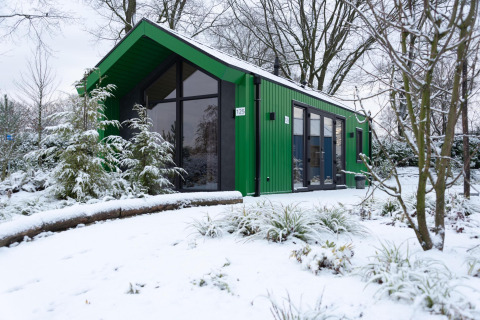 Chalet de chasse vert au parc de vacances Ackersate, Pays-Bas, entouré de neige hivernale.