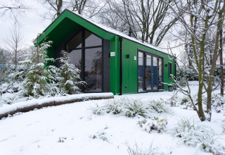 Chalet de caza verde en Holiday park Ackersate, Países Bajos, rodeado de nieve invernal.