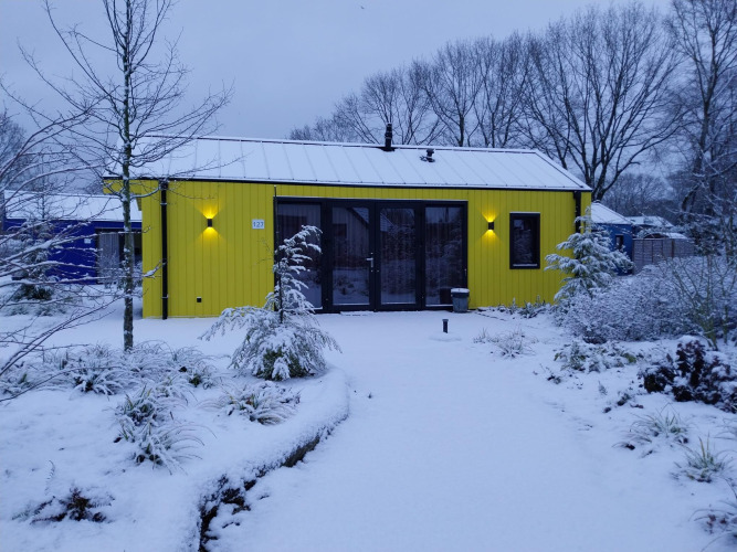 Gelbes Ferienhaus im Holiday Park Ackersate, Niederlande, im Schnee mit winterlicher Umgebung.