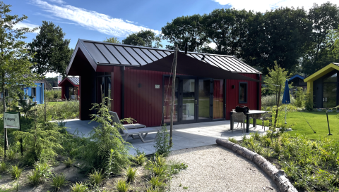 Hunting chalet at Holiday Park Ackersate in the Netherlands, featuring patio seating and lush garden.