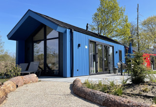 Blå jagthytte på Holiday park Ackersate i Holland, moderne design omgivet af natur og grønne træer.