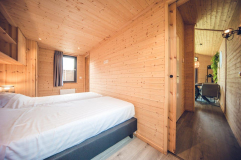 Dormitorio en cabaña de caza en Holiday park Ackersate, Países Bajos, con paredes de madera y camas gemelas
