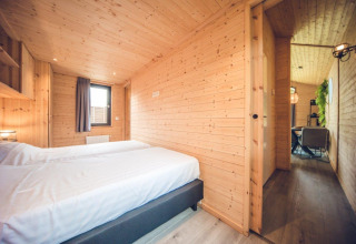 Dormitorio en cabaña de caza en Holiday park Ackersate, Países Bajos, con paredes de madera y camas gemelas