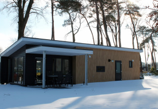 Lodge Forest Villa en Holiday park Ackersate, Países Bajos, visto desde fuera en invierno con nieve alrededor.