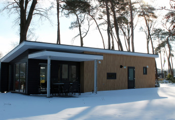 Lodge Forest Villa en Holiday park Ackersate, Países Bajos, visto desde fuera en invierno con nieve alrededor.