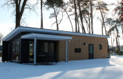 Forest Villa-Lodge im Ferienpark Ackersate, Niederlande, von außen im Winter mit Schnee bedeckt.