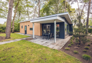 Moderne Forest Villa lodge met overdekt terras in Holiday park Ackersate, omringd door bomen in Nederland.