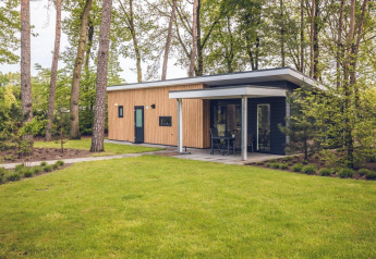 Moderne lodge Forest Villa hos Holiday park Ackersate, omgivet af grønt græs og træer i Holland.
