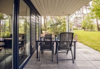 Terraza con mesa y sillas en Forest Villa, Holiday park Ackersate, Países Bajos, rodeada de naturaleza verde.