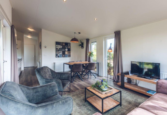Soggiorno nella Forest Villa al Holiday park Ackersate nei Paesi Bassi, arredamento moderno, TV e zona pranzo.
