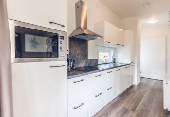 Modern kitchen interior of Forest Villa at Holiday park Ackersate, Netherlands, featuring sleek white cabinets.
