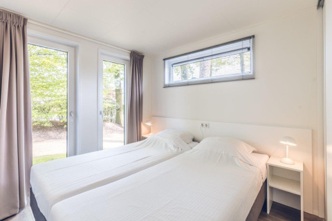 Dormitorio moderno y luminoso con dos camas individuales en Forest Villa, Holiday park Ackersate, Países Bajos.