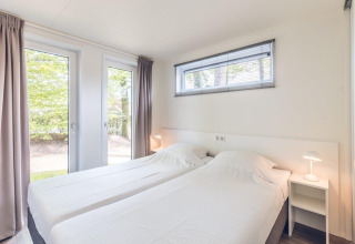 Dormitorio moderno y luminoso con dos camas individuales en Forest Villa, Holiday park Ackersate, Países Bajos.