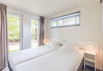 Lichte, moderne slaapkamer met twee eenpersoonsbedden in Forest Villa, Holiday park Ackersate, Nederland.