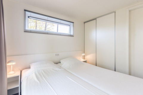 Dormitorio luminoso y moderno en Forest Villa, Holiday park Ackersate, Países Bajos, con dos camas individuales.