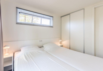 Dormitorio luminoso y moderno en Forest Villa, Holiday park Ackersate, Países Bajos, con dos camas individuales.