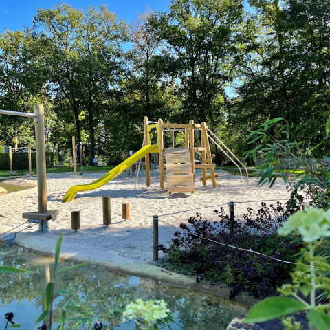 Playground with wooden equipment and yellow slide at safari tent Tentvilla in Holiday park De Witte Berg, Netherlands