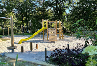 Speeltuin met houten speeltoestellen en gele glijbaan bij Tentvilla in recreatiepark De Witte Berg, Nederland
