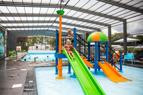 Niños juegan en un tobogán colorido en la piscina cubierta del Holiday park De Witte Berg, Países Bajos.