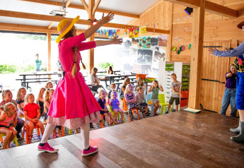 Kinderen kijken naar een optreden in een safaritent in Vakantiepark De Witte Berg, Nederland.