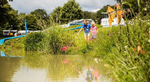 Kinder spielen am Teich beim Safarizelt Tentvilla im Ferienpark De Witte Berg in den Niederlanden.