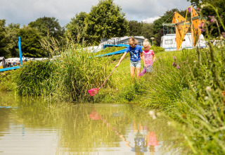 Børn leger ved en sø nær safari teltet Tentvilla i ferieparken De Witte Berg, Holland, om sommeren.