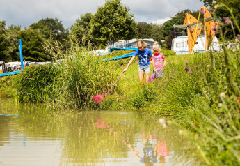 Kinderen spelen aan de vijver bij safaritent Tentvilla op vakantiepark De Witte Berg in Nederland.
