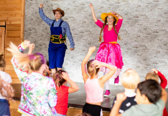 Bambini partecipano a uno spettacolo vivace con due attori in costume nel Tentvilla, De Witte Berg, Paesi Bassi.