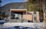 Chalet moderne de Wulfenia au Pressegger See, Autriche, en hiver avec montagnes enneigées au fond.