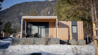 Moderne lodge bij Wulfenia, Pressegger See, Oostenrijk, in de winter met besneeuwde bergen op de achtergrond.