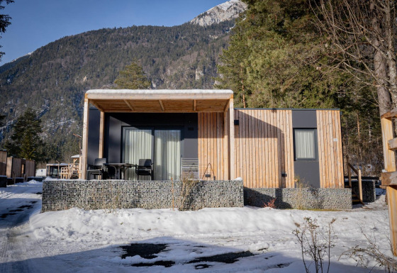 Chalet moderne de Wulfenia au Pressegger See, Autriche, en hiver avec montagnes enneigées au fond.