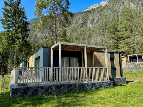 Buitenaanzicht van de moderne Wulfenia-lodge, omringd door bomen en bergen in een schilderachtige omgeving.