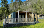 Outdoor view of the modern Wulfenia lodge, surrounded by trees and mountains in a picturesque setting.