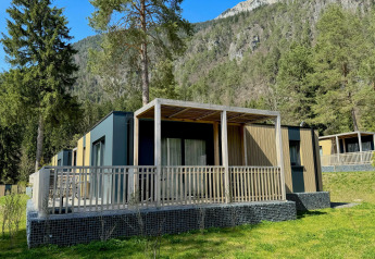 Buitenaanzicht van de moderne Wulfenia-lodge, omringd door bomen en bergen in een schilderachtige omgeving.