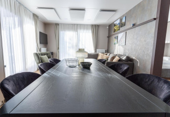 Moderne woonkamer in Wulfenia Lodge aan de Pressegger See, Oostenrijk, met eettafel, bank en grote ramen.