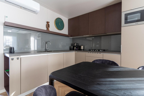 Cocina moderna en la cabaña Wulfenia junto al lago Pressegger See, Austria, con mesa de comedor y gabinetes.