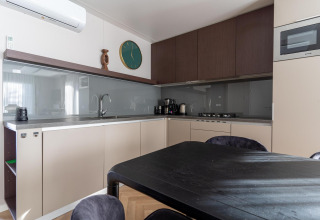 Cocina moderna en la cabaña Wulfenia junto al lago Pressegger See, Austria, con mesa de comedor y gabinetes.