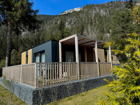 Moderne Wulfenia-lodge bij Pressegger See in Oostenrijk, omringd door bergen en groene bomen.