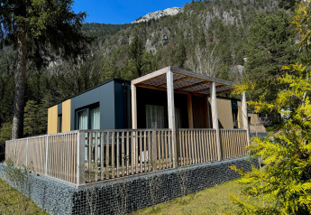 Moderne Wulfenia-lodge bij Pressegger See in Oostenrijk, omringd door bergen en groene bomen.