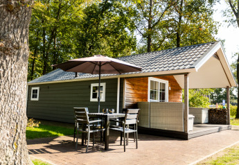 En hyggelig Forest Lodge ved ferieparken De Witte Berg i Holland, med terrasse, bord og parasol udenfor.