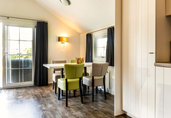 Bright dining area in Forest Lodge at Holiday park De Witte Berg, Netherlands, with modern chairs and windows.