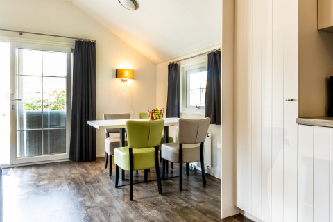 Bright dining area in Forest Lodge at Holiday park De Witte Berg, Netherlands, with modern chairs and windows.