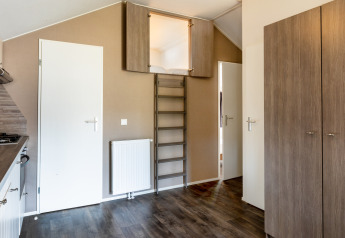 Indvendigt billede af Forest Lodge på feriepark De Witte Berg med stige til hems og moderne interiør.