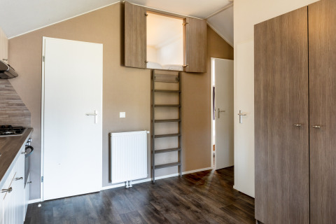 Interieur van Forest Lodge op vakantiepark De Witte Berg met trap naar slaapzolder en moderne keuken.