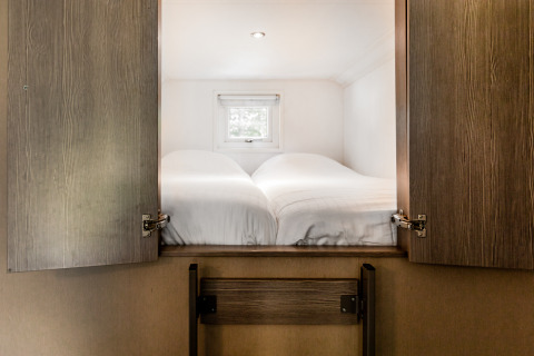 Habitación con dos camas individuales tras puertas de madera en Forest Lodge, Holiday park De Witte Berg, Países Bajos.