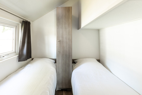 Habitación con dos camas individuales y armario en Forest Lodge, Holiday park De Witte Berg, Países Bajos.
