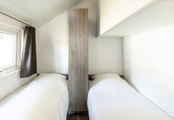Habitación con dos camas individuales y armario en Forest Lodge, Holiday park De Witte Berg, Países Bajos.