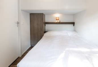Modernes Schlafzimmer in der Forest Lodge im Ferienpark De Witte Berg, Niederlande, mit weißer Bettwäsche.