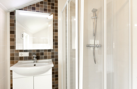 Salle de bains lumineuse avec lavabo, miroir et douche au Forest Lodge du parc De Witte Berg, Pays-Bas.