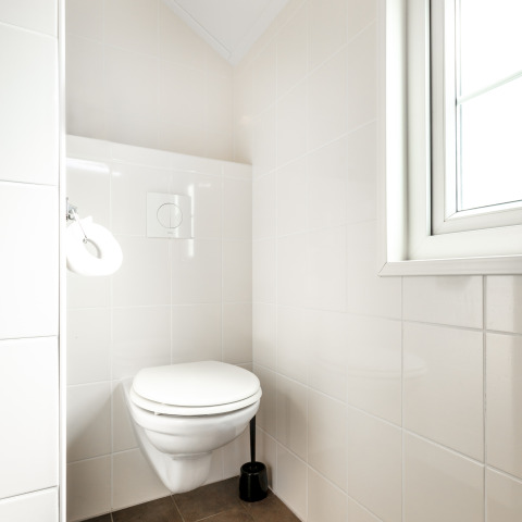 Bright, modern bathroom with wall-mounted toilet at Forest Lodge, Holiday park De Witte Berg, Netherlands.